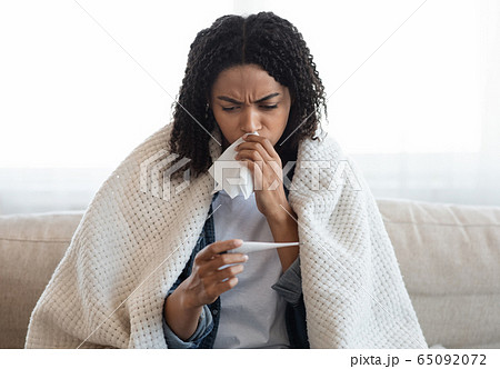 Coronavirus Symptoms. Sick black woman checking her body temperature at home Coronavirus Symptoms. Sick black woman checking her body temperature at home 65092072