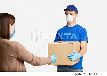 Client in protective mask, takes box from courier Client in protective mask, takes box from courier 65092326