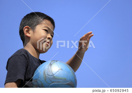 サッカーボールを抱える小学生 5年生 と青空の写真素材