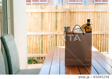 Paper bag with food on the wooden table in the backyard of a house. 65095256