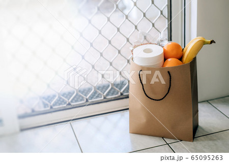 Paper bag with food and toilet paper on the floor at the entrance to house. Paper bag with food and toilet paper on the floor at the entrance to house. 65095263