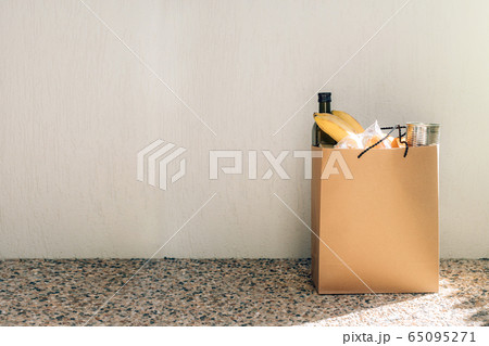 Paper bag with food on the floor next to the wall of house. Paper bag with food on the floor next to the wall of house. 65095271