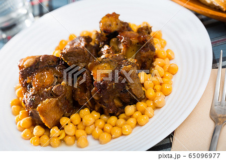 Braised oxtails with chickpeas on a white plate 65096977