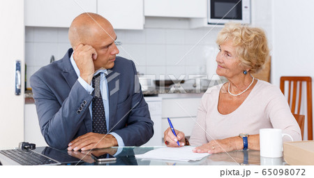 Mature woman and agent fills in documents 65098072