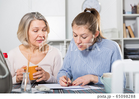 Woman with daughter filling documents Woman with daughter filling documents 65098288
