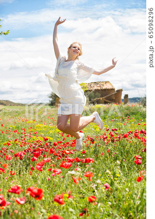 Nice young female jumping in poppy field 65098296