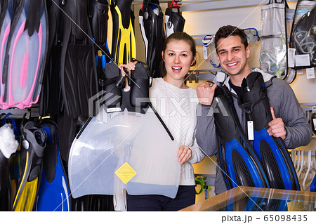 Man and woman are standing with modern diving flippers in the store. 65098435