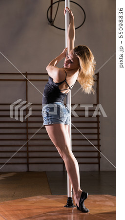 Attractive sports girl dancer engaged on pylon at gym Attractive sports girl dancer engaged on pylon at gym 65098836