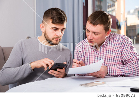 Serious men with documents and phone at home table 65099073