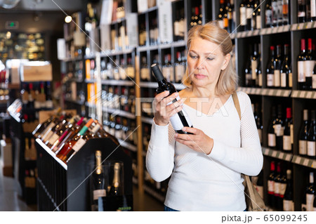 Woman choosing bottled wine in wineshop Woman choosing bottled wine in wineshop 65099245