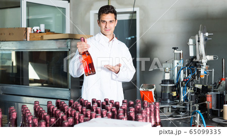 young man employee standing in final section of wine production on factory young man employee standing in final section of wine production on factory 65099335