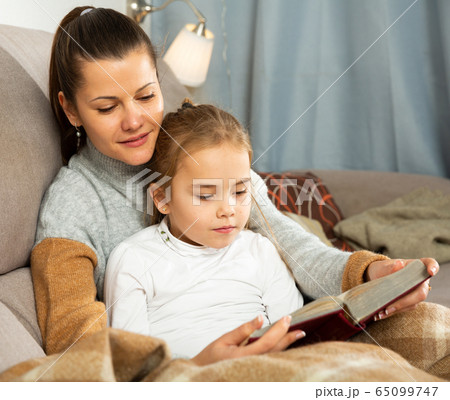 Young woman reading an interesting book with daughter Young woman reading an interesting book with daughter 65099747