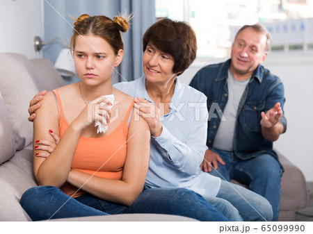 Parents are comforting the upset adult daughter on sofa Parents are comforting the upset adult daughter on sofa 65099990
