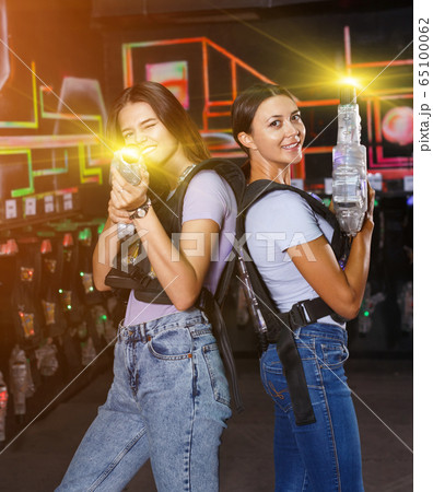 Two girls standing back and holding guns during laser tag game i Two girls standing back and holding guns during laser tag game i 65100062