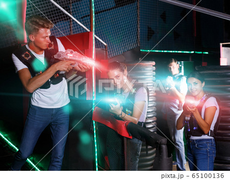 friends playing laser tag game with laser guns near tires 65100136