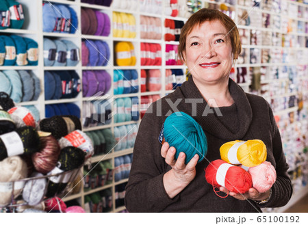Positive mature female with colorful yarn in shop Positive mature female with colorful yarn in shop 65100192