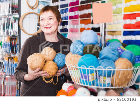 Senior female choosing colorful yarn in shop 65100193