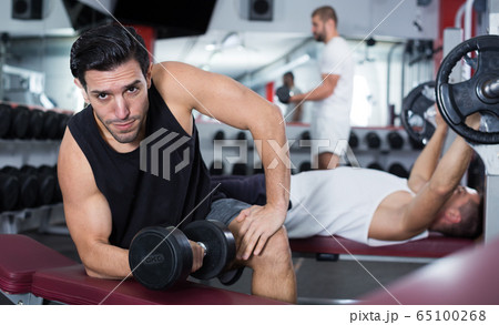 Guy during workout in gym with dumbbells Guy during workout in gym with dumbbells 65100268