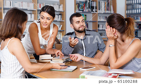 Friendly group of young students studying in university library with female tutor Friendly group of young students studying in university library with female tutor 65100288