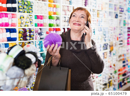 Woman with needlework accessories and talking on phone 65100479