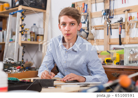 teenager smiling and working with wood in the workshop 65100591