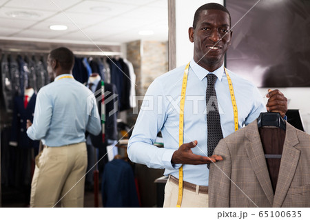 Male customer demonstrating his choice of suit in shop 65100635