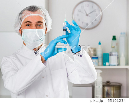 Man nurse preparing syringe for injection in hospital 65101234
