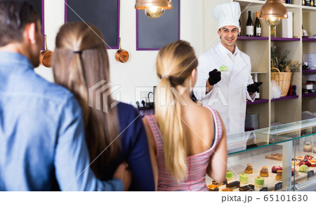 Male pastry chef helping customers to choose sweets 65101630