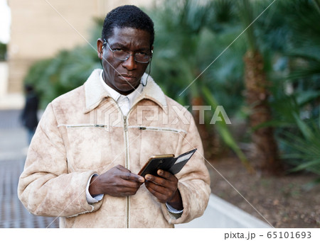 Man in overcoat using smartphone 65101693