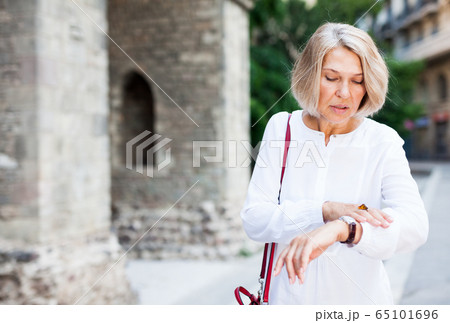 Hurrying woman looks at her watch and talking on the phone 65101696