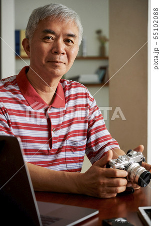 Man uploading photos from camera on laptop 65102088