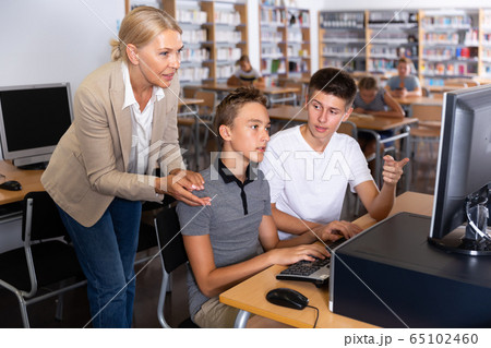 Children and adult teacher working with computers 65102460