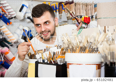 Young male is deciding on best brush for painting and decorating 65102481