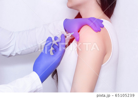 Doctor makes an injection of blockade of chondroprotector and anti-inflammatory drug in the girl's sore shoulder, white background, close-up, ozone therapy 65105239