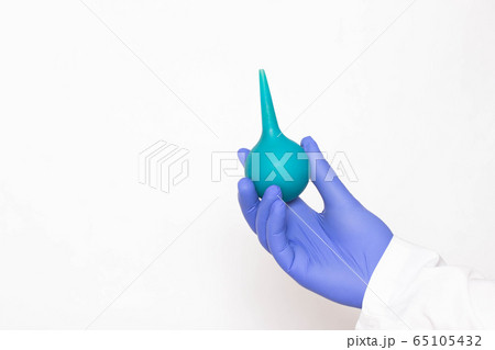 Doctor holds an enema in his hand on a white background, the concept of treating chronic prostatitis with microclysmic action on the inflamed prostate, copy space Doctor holds an enema in his hand on a white background, the concept of treating chronic prostatitis with microclysmic action on the inflamed prostate, copy space 65105432