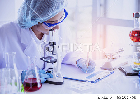 Female scientist look at microscope, science test 65105709