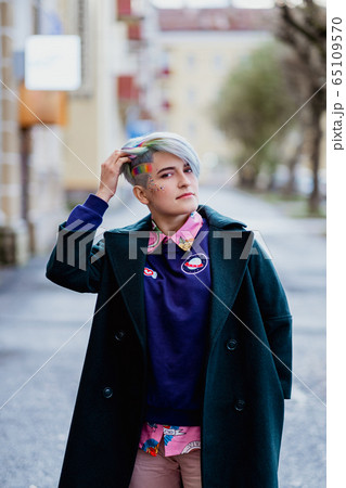 Portrait of a young beautiful woman with a short haircut and dyed hair. Grey main color and yellow, green, blue and red hair color. Portrait of a young beautiful woman with a short haircut and dyed hair. Grey main color and yellow, green, blue and red hair color. 65109570