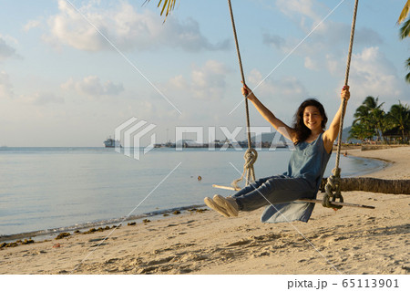 The girl on the beach rides on a swing during The girl on the beach rides on a swing during 65113901