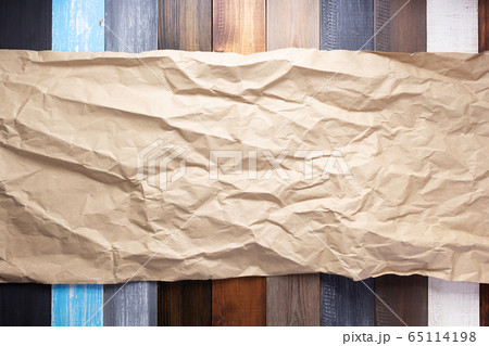 wrinkled paper at wooden board  background 65114198
