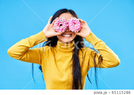 Attractive woman having fun with donuts 65115286