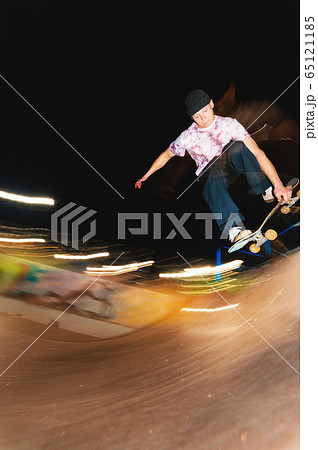 A young skater at night in a skatepark does the trick on the railing. X-ray culture nightlife concept A young skater at night in a skatepark does the trick on the railing. X-ray culture nightlife concept 65121185