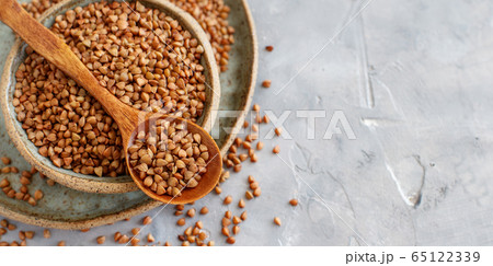 Raw dry buckwheat grain in a bowl with a spoon Raw dry buckwheat grain in a bowl with a spoon 65122339