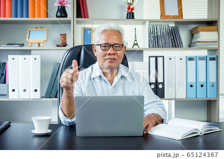 Happy Asian elderly man sitting in front of a Happy Asian elderly man sitting in front of a 65124367