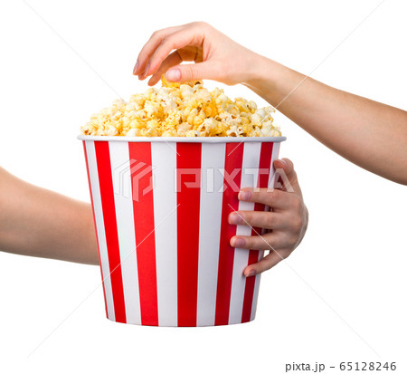 Woman hand taking popcorn from striped bucket isolated on white background Woman hand taking popcorn from striped bucket isolated on white background 65128246