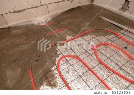 A worker pours concrete underfloor heating in the A worker pours concrete underfloor heating in the 65128653