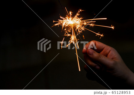 Female hand holding a burning sparkler, Christmas 65128953
