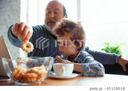 Grandfather and his grandson spending time insulated at home, stadying, watching cinema, shopping together Grandfather and his grandson spending time insulated at home, stadying, watching cinema, shopping together 65129018