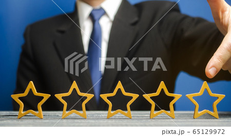 Businessman points to the fifth star. The concept of the rating of hotels and restaurants. The evaluation of visitors. Quality level, good service. Best customer rating. Feedback. Satisfaction 65129972