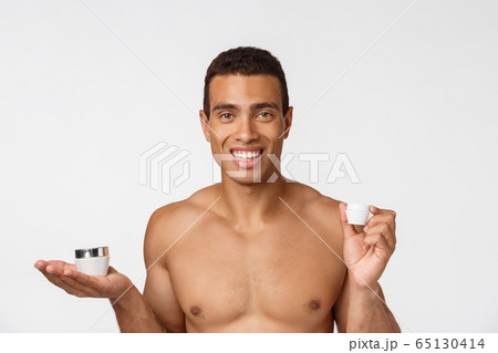 Photo of shirtless african american man smiling and holding cream isolated over white background Photo of shirtless african american man smiling and holding cream isolated over white background 65130414
