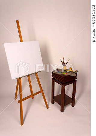 Blank canvas on Easel. Clean cloth stretched on subframe with copy space. Tripod with empty white canvas for new oil painting. Squeeze out oil paints on a palette. Blank canvas on Easel. Clean cloth stretched on subframe with copy space. Tripod with empty white canvas for new oil painting. Squeeze out oil paints on a palette. 65131522